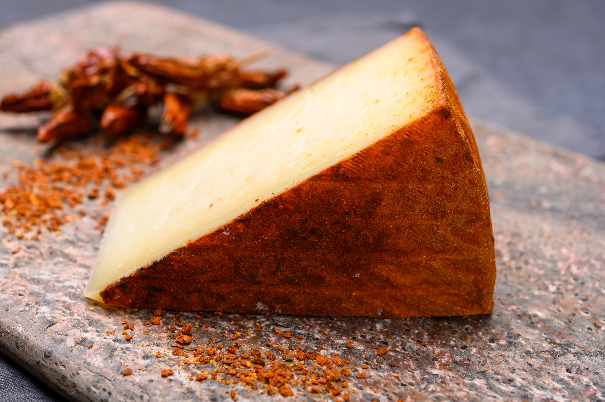 Cheese collection, piece of Spanish manchego cheese made from cow milk with red paprika close up
