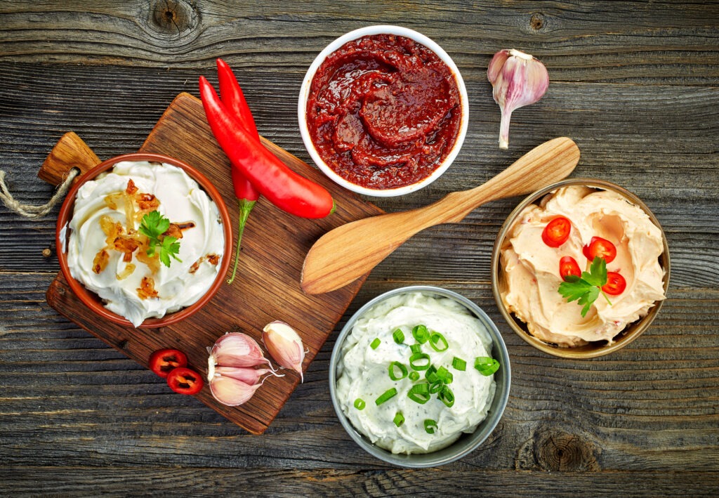 various dip sauces on wooden table, top view